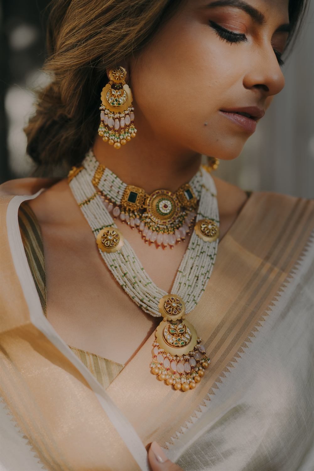 Model wearing a layered antique gold necklace with pearls and kundan earrings