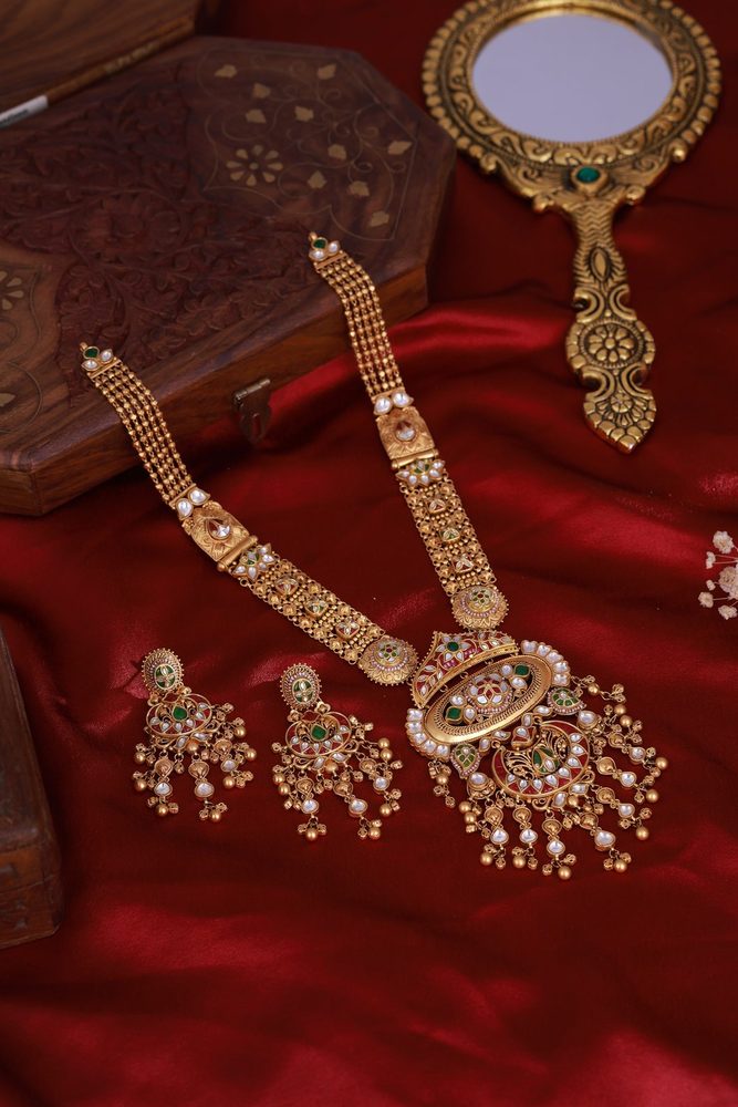 Antique gold long necklace and earrings displayed on red silk