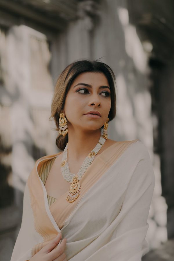 Model in an ivory saree wearing a long pearl and gold haar