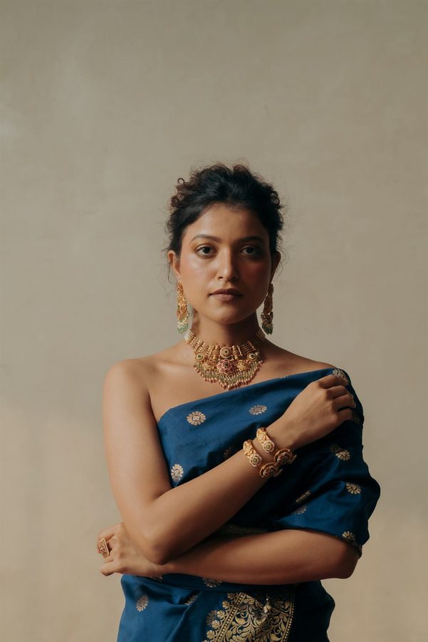 Model in a blue saree wearing a gold choker and bangles